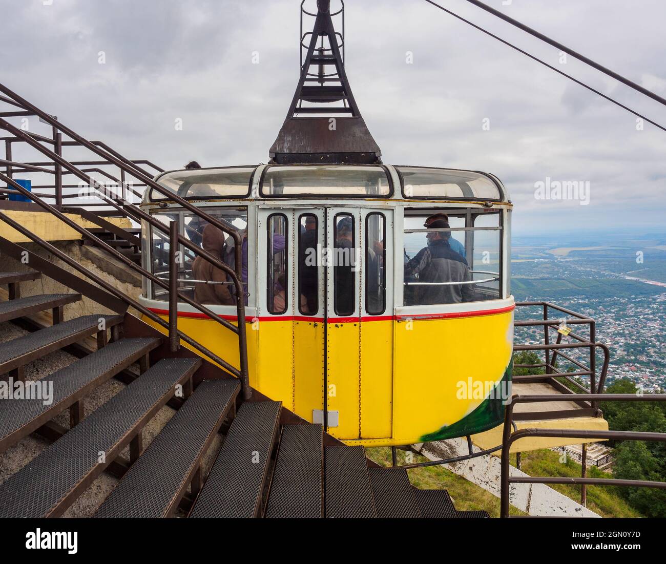 Old yellow cable car on the upper station above the town with people Stock Photo