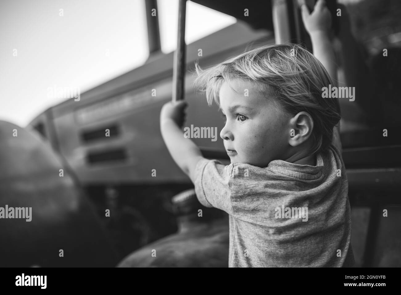 Boy climbs on a tractor, black and white Stock Photo