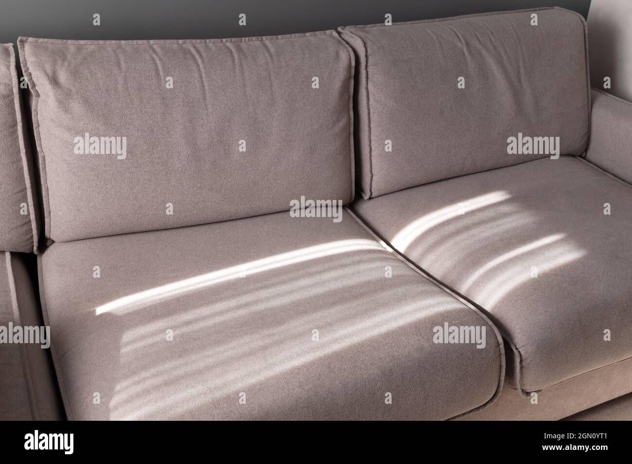 Wide sofa with sunlight pattern on it, abstract blank interior fragment Stock Photo