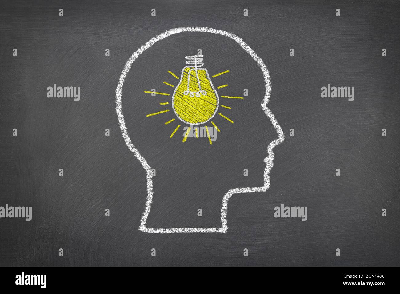 A chalk sketch on a blackboard of a human head and lightbulb that represents thoughts and ideas, for use as any science theme or consideration of how Stock Photo