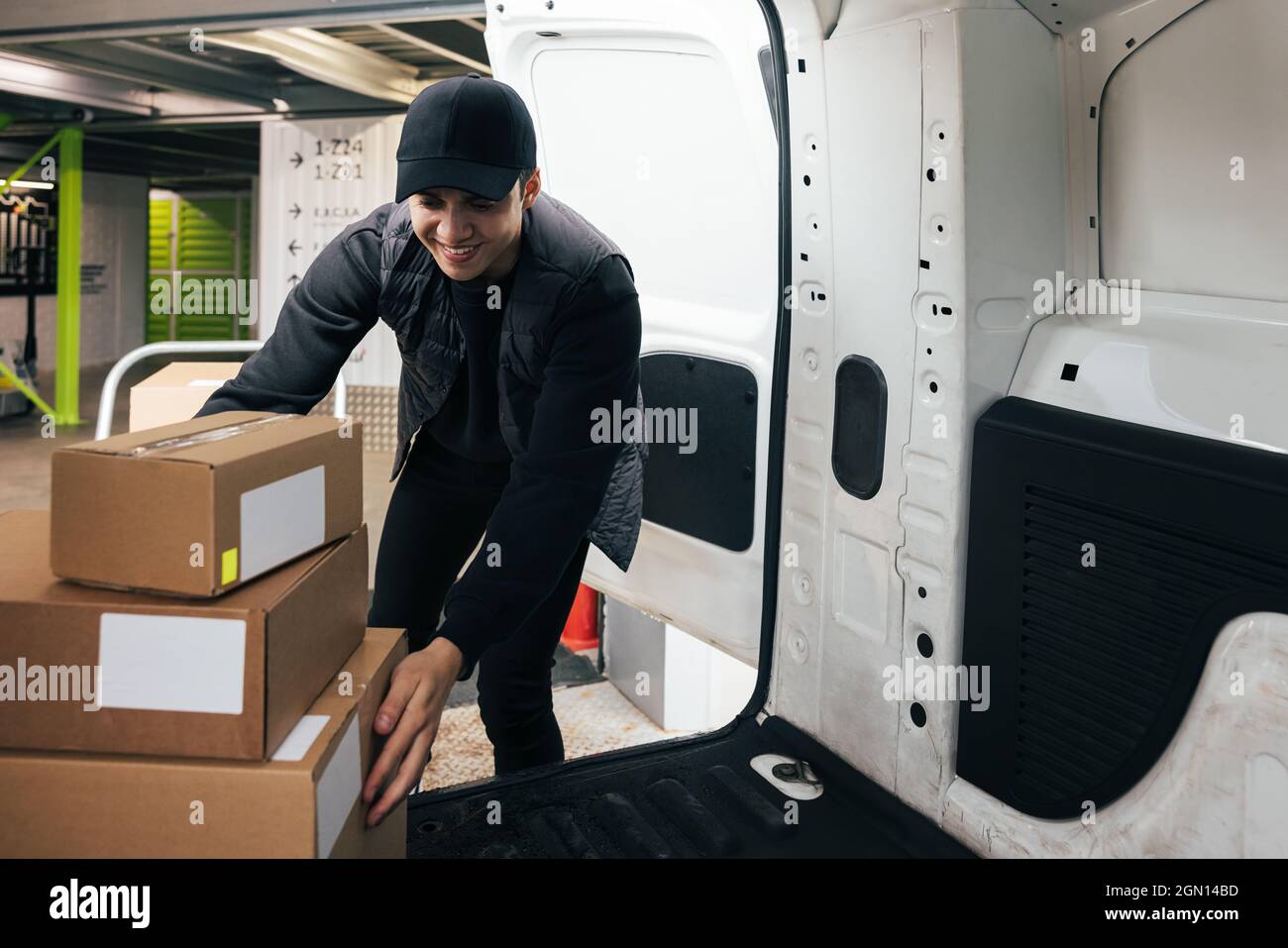 Smiling male courier working in warehouse upload boxes into a van for delivery Stock Photo Alamy