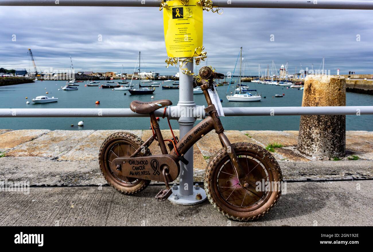 A bike sprayed gold by the group, Heroes Golden Bikes, to raise awareness of childhood cancer. Seen here chained to railings in Howth, Dublin. Stock Photo