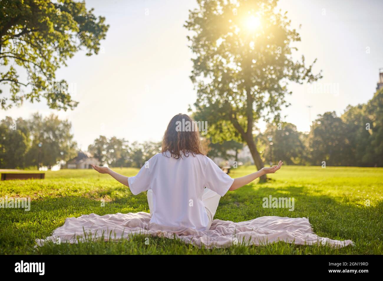 A girl sitting on a lotus pose and meditating in the park Stock Photo ...