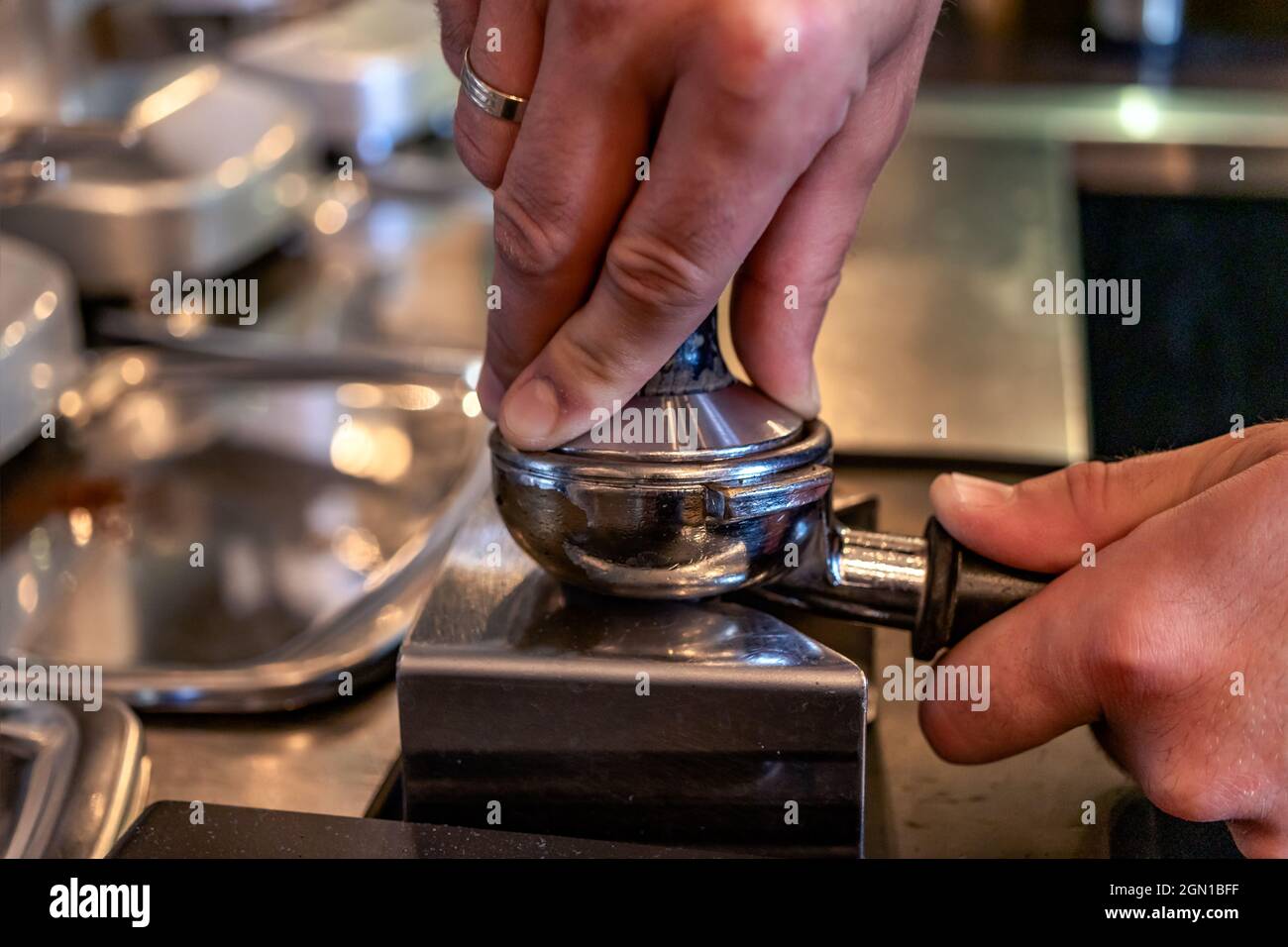 Barista pressing grounded coffee for making a cup of espresso using a ...