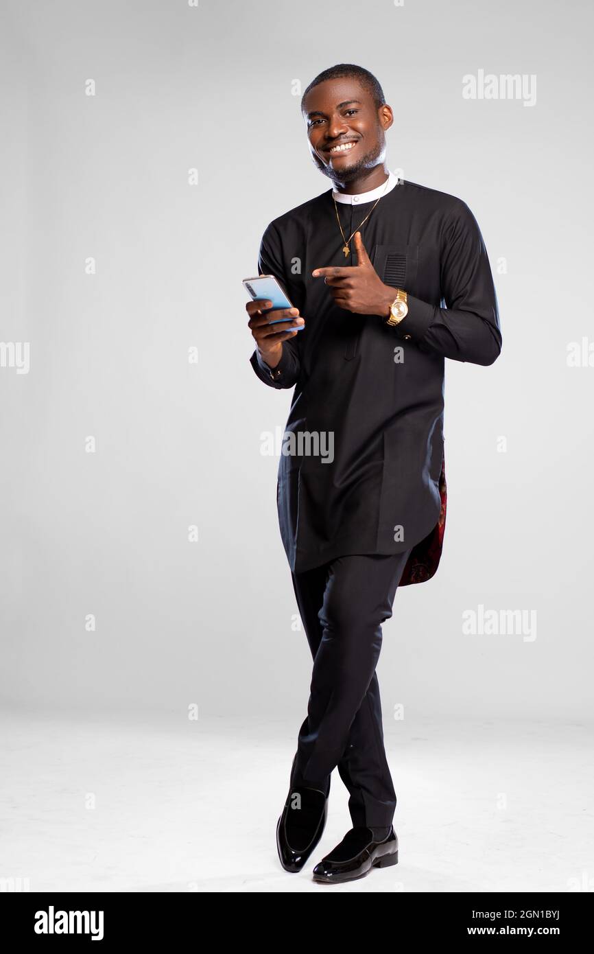 handsome young african man smiling while using his phone and pointing to it Stock Photo