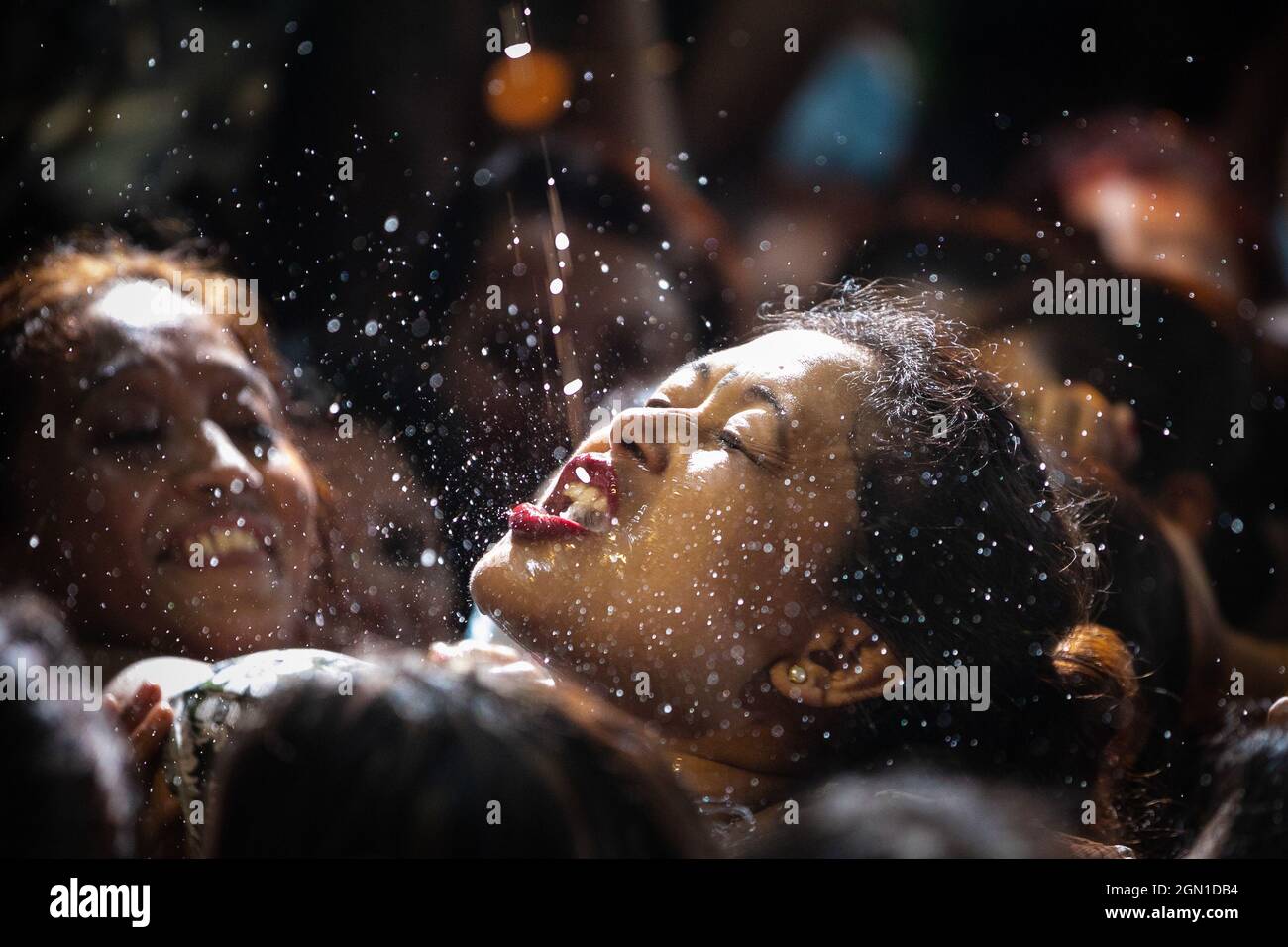 Kathmandu, Nepal. 21st Sep, 2021. Nepalese women struggle to drink homemade alcohol from the mouth of Deity Swet Bhairav as blessings during Indra Jatra festival.The annual festival, named after Indra, the god of rain and heaven, is celebrated by worshipping, rejoicing, singing, dancing and feasting in Kathmandu Valley to mark the end of monsoon season. Indra, the living goddess Kumari and other deities are worshipped during the festival. Credit: SOPA Images Limited/Alamy Live News Stock Photo