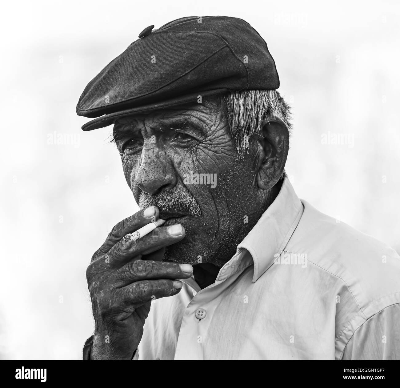 KAYSERI, TURKEY - Jul 15, 2021: A greyscale shot of middle-aged man smoking outside in Kayseri, Turkey Stock Photo