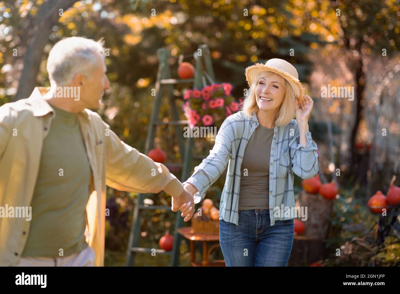 Romantic senior couple holding hands and walking in the park on warm autumn day, happily retired, free space Stock Photo