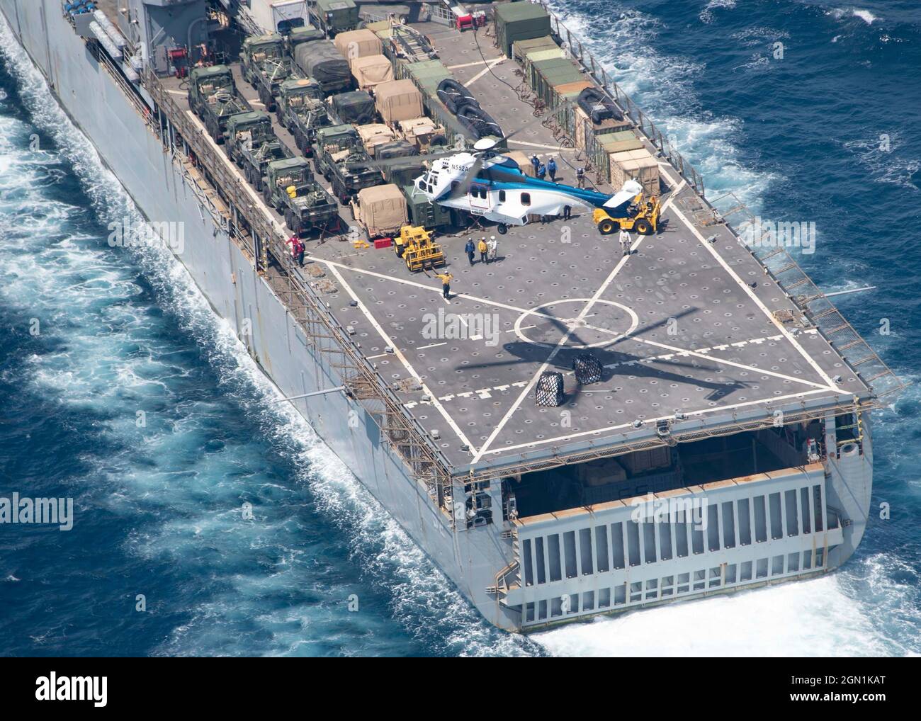 A U.S. Navy Airbus Helicopter EC225 LP Super Puma helicopter drops dry cargo and ammunition supplies from the USNS Wally Schirra, on the deck of the Harpers Ferry-class dock landing ship USS Pearl Harbor () a replenishment-at-sea with the Wasp-class amphibious assault ship USS Essex  September 18, 2021 in the Arabian Sea. Stock Photo