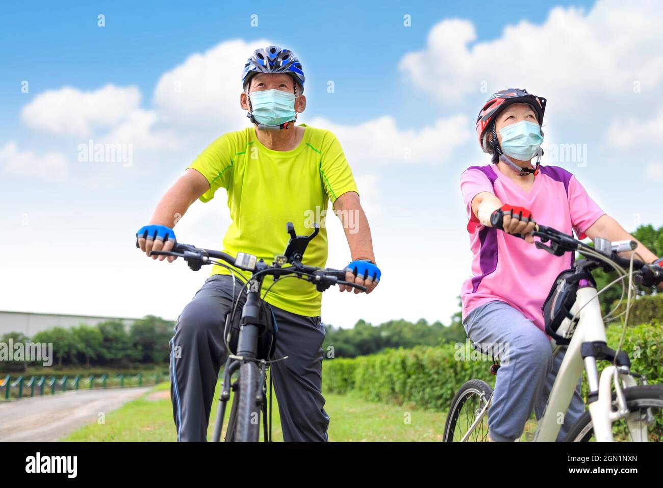 Asian Senior couple  wearing medical mask and riding bicycle in the park Stock Photo