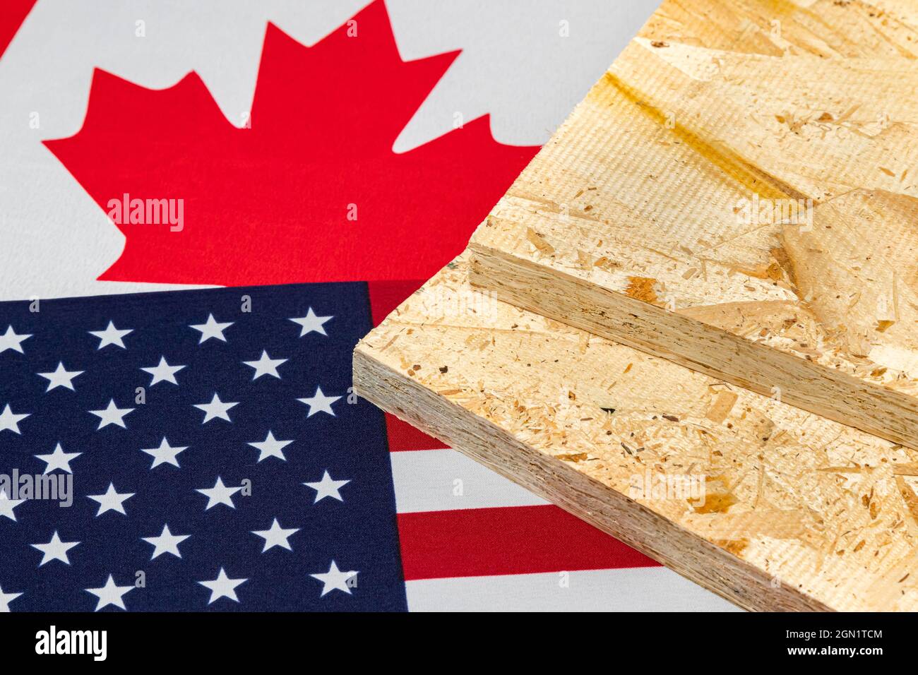 OSB, oriented strand board, plywood on flag of Canada and United States of America. Trade war, tariffs, fair trade and lumber, logging industry concep Stock Photo