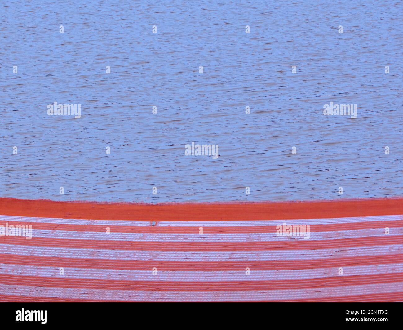 Fluorescent orange and white striped streamer, isolating the lake from users Stock Photo