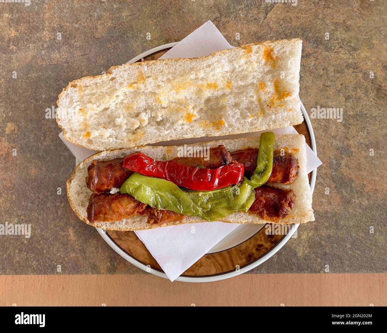 Top view of roasted chorizo sausages with cooked peppers on bread on the plate Stock Photo