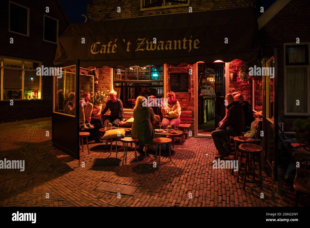 People sit in front of Café &#39;t Zwaantje and enjoy beer at night, West Terschelling, Terschelling, West Frisian Islands, Friesland, Netherlands, Eu Stock Photo