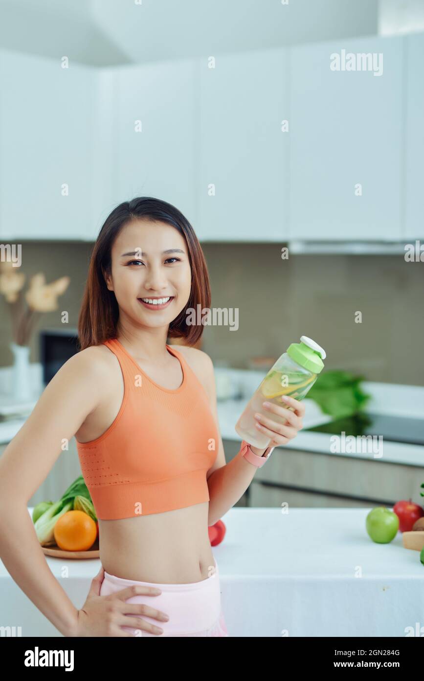 Young Asian woman holding detox juice bottle in the kitchen. Stock Photo
