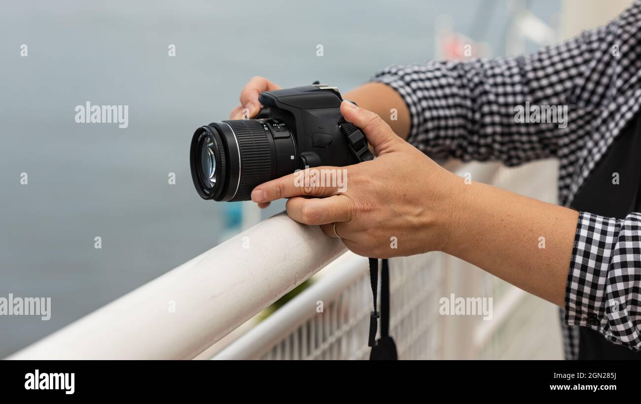 Female hands holding photo camera ready for taking photos outdoor. Stock Photo