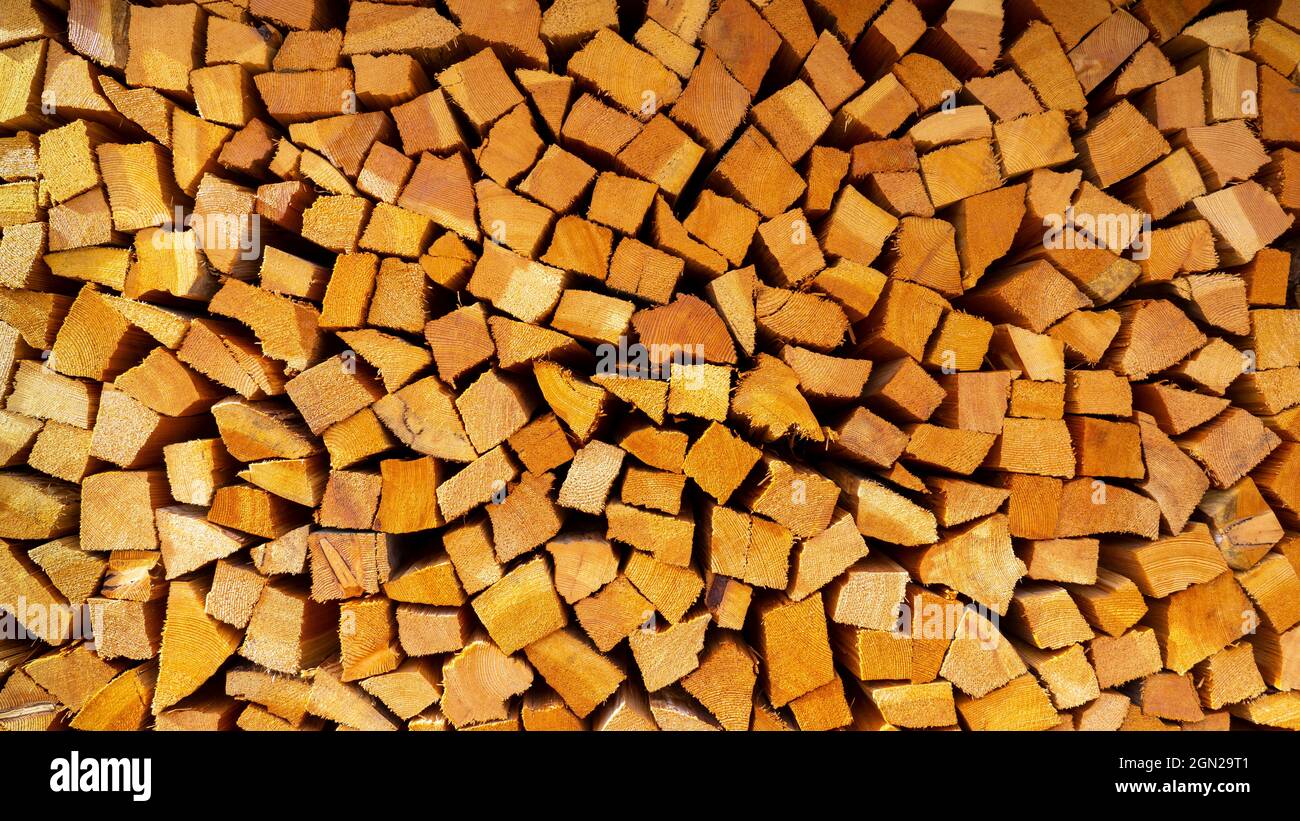 Firewood cut and stacked. Wall of wooden pieces. Warm colors with shades of brown. Wood stacked