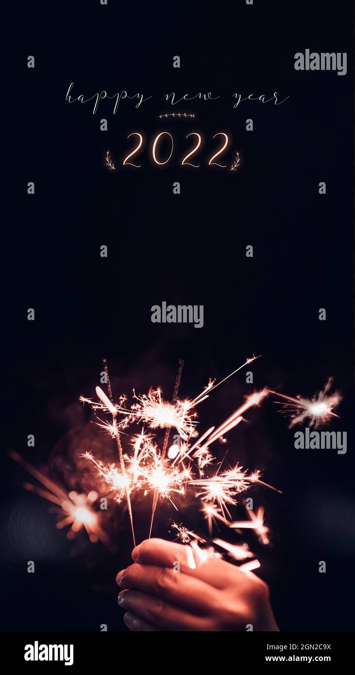 Make a wish new year 2022 with hand holding burning Sparkler firework blast with on a black bokeh background at night,holiday celebration event party. Stock Photo