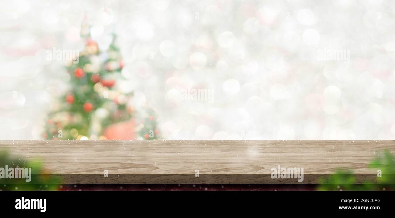 Merry Christmas wood table top at blur bokeh xmas tree decor with string light background,Winter banner backdrop for holiday greeting card Stock Photo