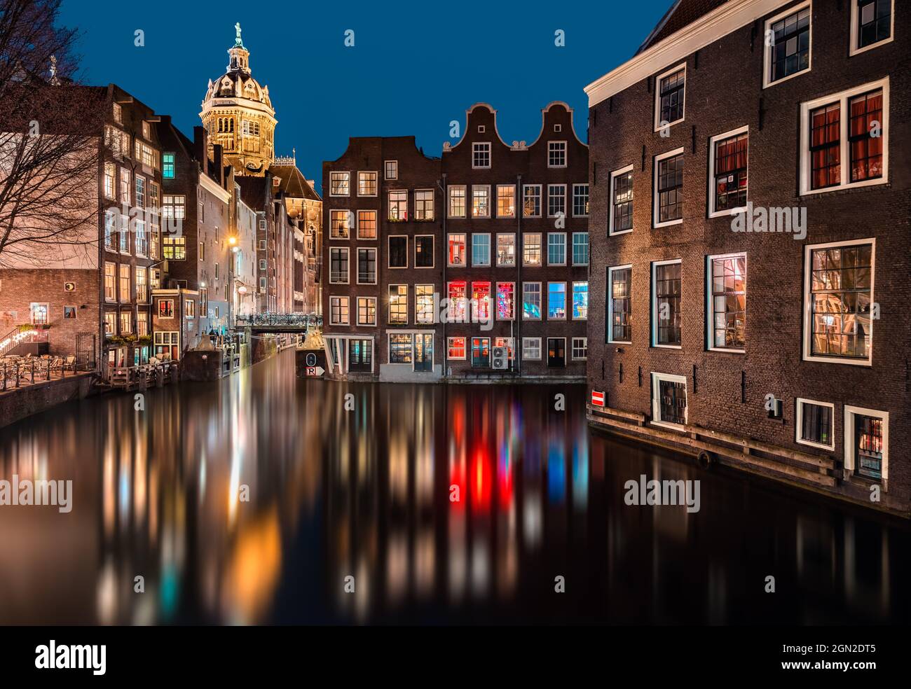 NETHERLANDS, AMSTERDAM, AMSTERDAM NIGHTLIFE WITH TYPICAL CANAL HOUSES AND CHURCH DURING BLUE HOUR Stock Photo