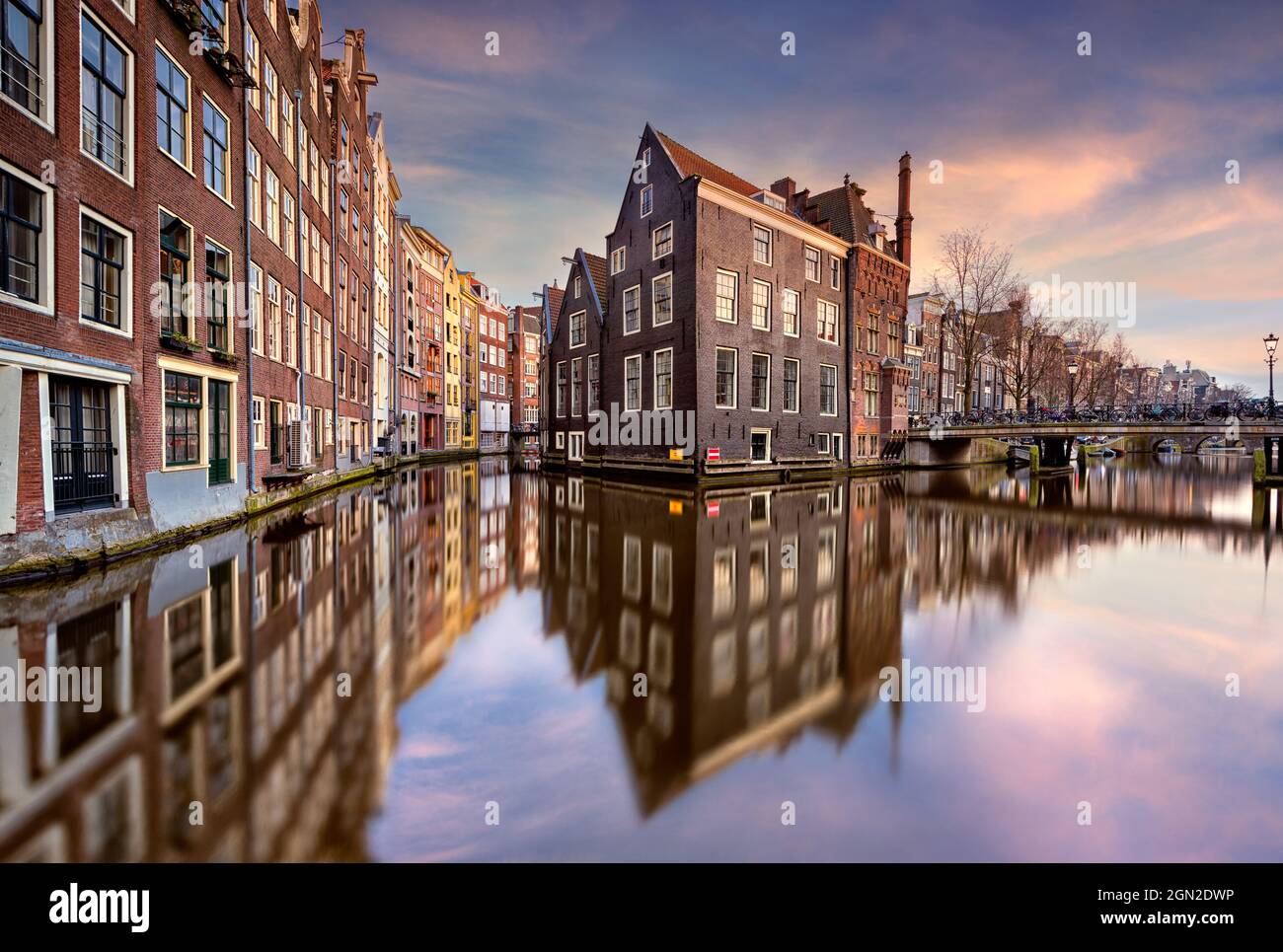 NETHERLANDS, AMSTERDAM, TYPICAL HOUSES AND THEIR REFLECTIONS ON THE CANAL AT SUNSET Stock Photo