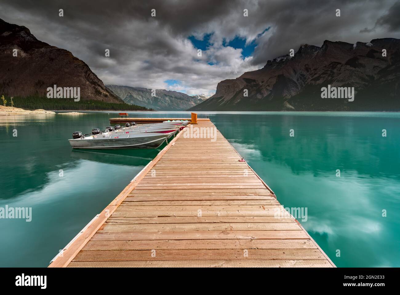 CANADA, ALBERTA, BANFF PARK, LAKE MINNEWANKA. WOODEN PONTOON WITH MOTOR BOATS MOORED ON LAKE MINNEWANKA WITH MONT GIROUARD IN THE BACKGROUND UNDER A S Stock Photo