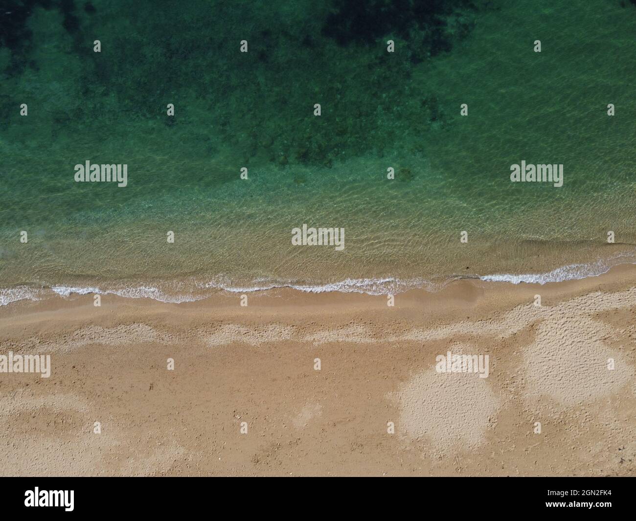 Beautiful remote beach with crystal clear azure water, aerial view. Untouched nature and hidden sandy beach with seagulls. Motion blur on small waves Stock Photo