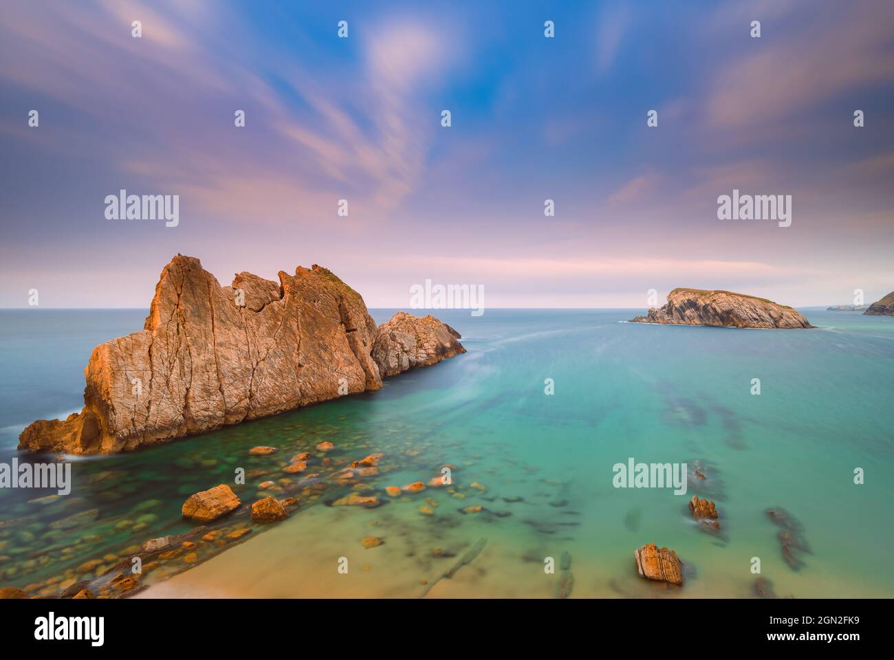 SPAIN, CANTABRIA, LIENCRES. VIEW FROM ABOVE OF ARNIA BEACH WITH ITS CUT ROCKS AND TURQUOISE WATER AT SUNSET Stock Photo