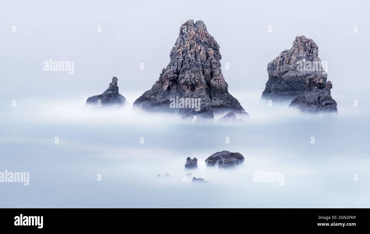 SPAIN, CANTABRIA. ISOLATED ROCKS IN THE OPEN SEA IN LOS URROS PHOTOGRAPHED IN LONG EXPOSURE WITH A MINIMALIST ASPECT Stock Photo
