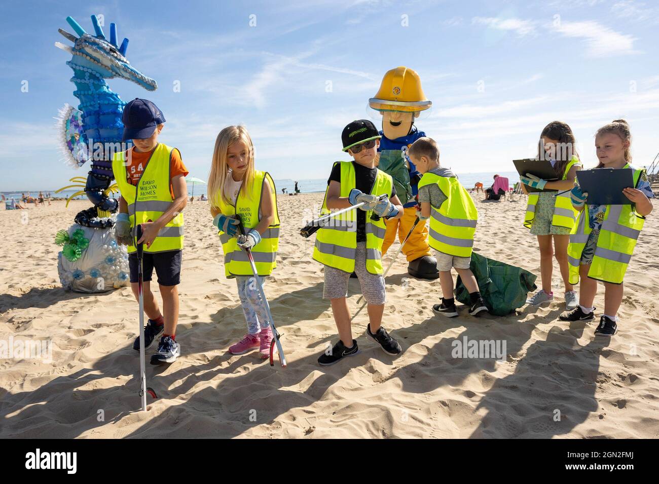 EDITORIAL USE ONLY A woman dressed as Fireman Sam and children from Bearwood Primary School help the Marine Conservation Society collect litter for the ???Great British Beach Clean??? in Sandbanks, Dorset. Picture date: Tuesday September 21, 2021. Stock Photo