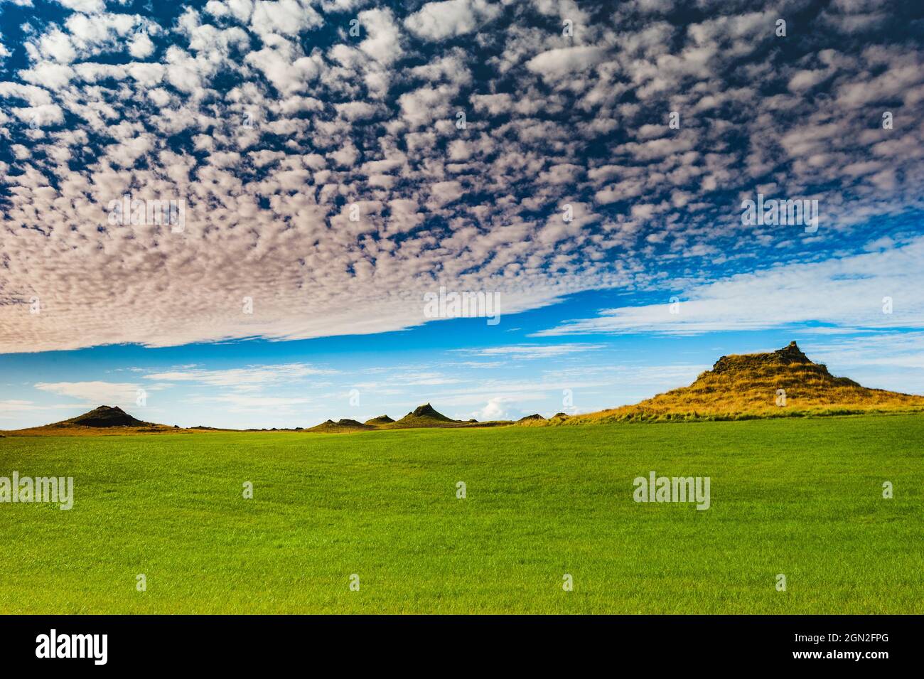 ICELAND, MEADOW WITH HILLS UNDER A CLOUDY SKY Stock Photo