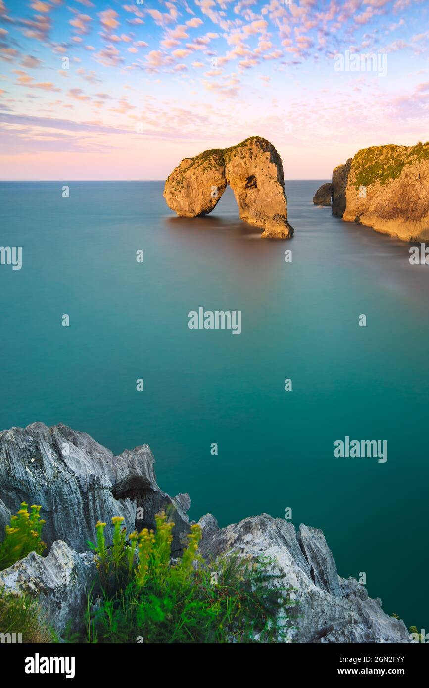 SPAIN, ASTURIAS. ROCK FORMATION IN THE MIDDLE OF THE OCEAN AT SUNSET Stock Photo