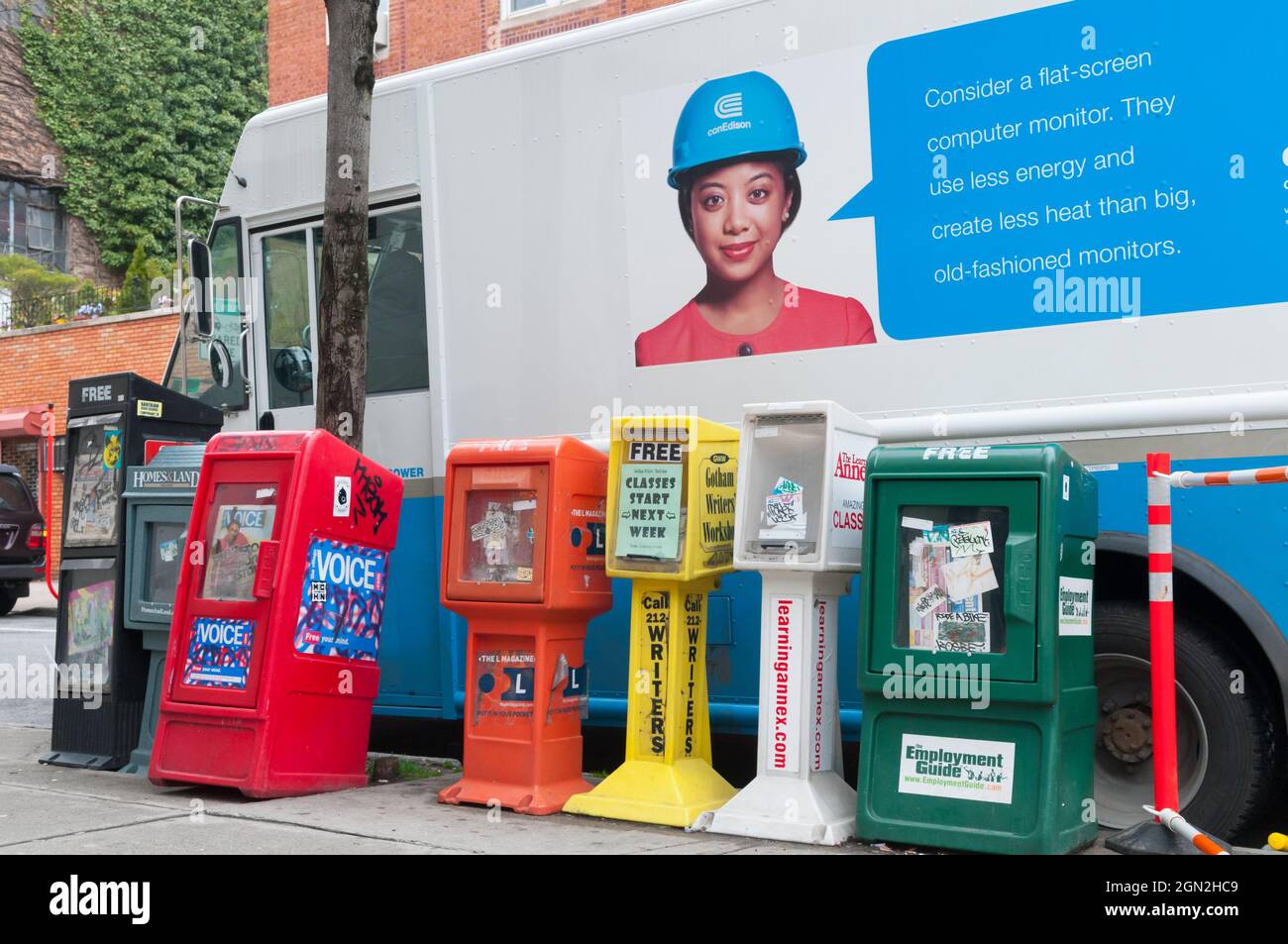 USA, NEW YORK, MANHATTAN, COLORED NEWSPAPER DISPENSERS ON A SIDEWALK WITH A TRUCK IN THE BACKGROUND Stock Photo