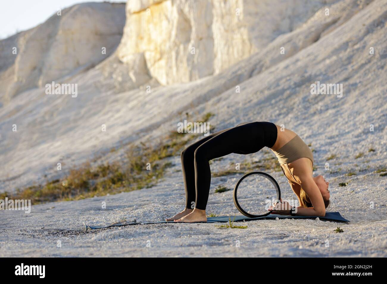 Young woman practicing yoga at white cliffs in the morning. Wheel pose with copy space. Stock Photo
