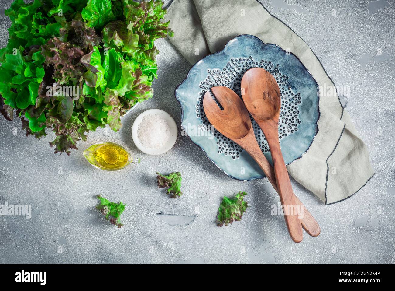 Modern ceramic bowl with wooden salad cutlery and bowl of lettuce on