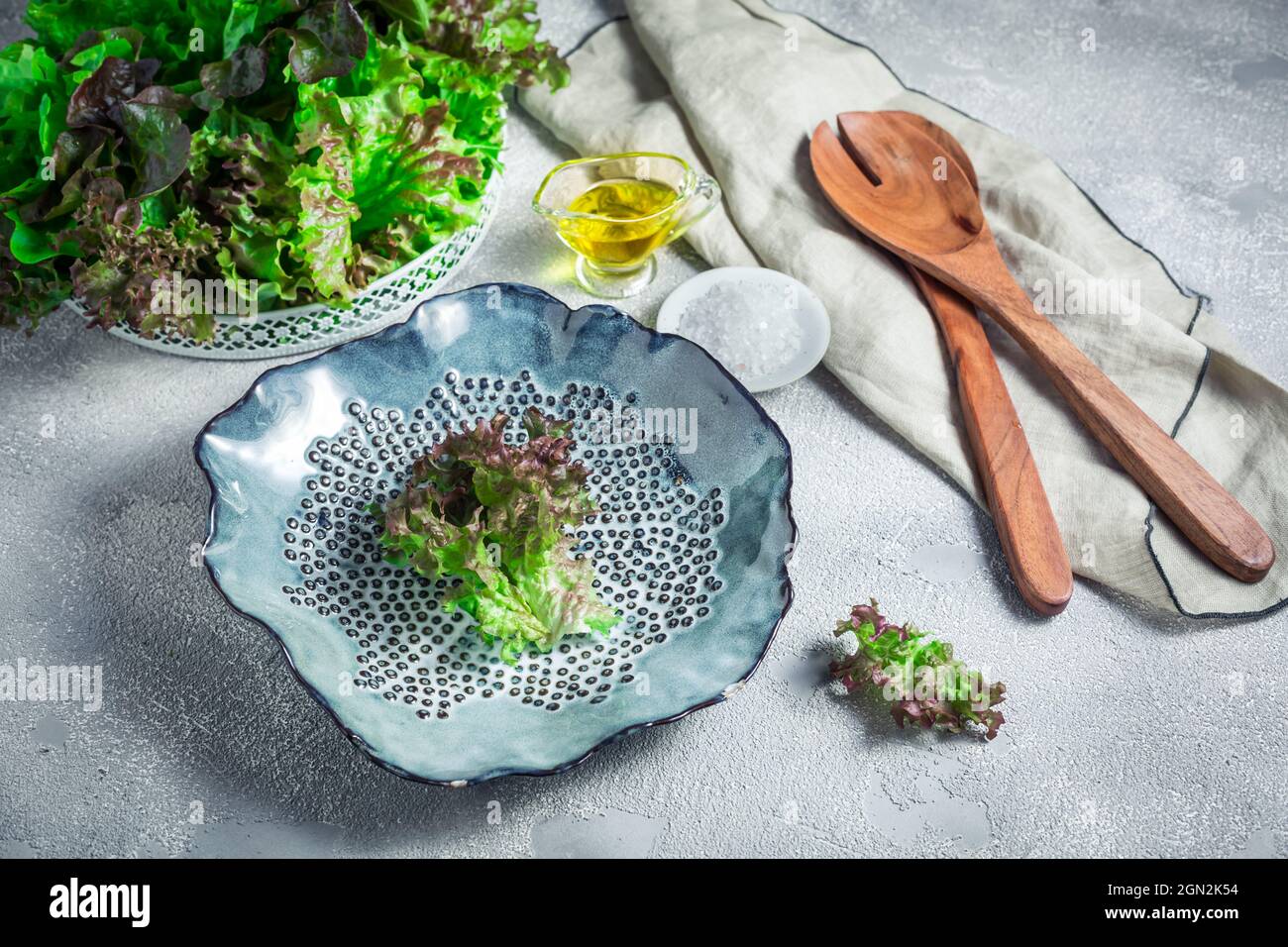 Modern ceramic bowl with wooden salad cutlery and bowl of lettuce on