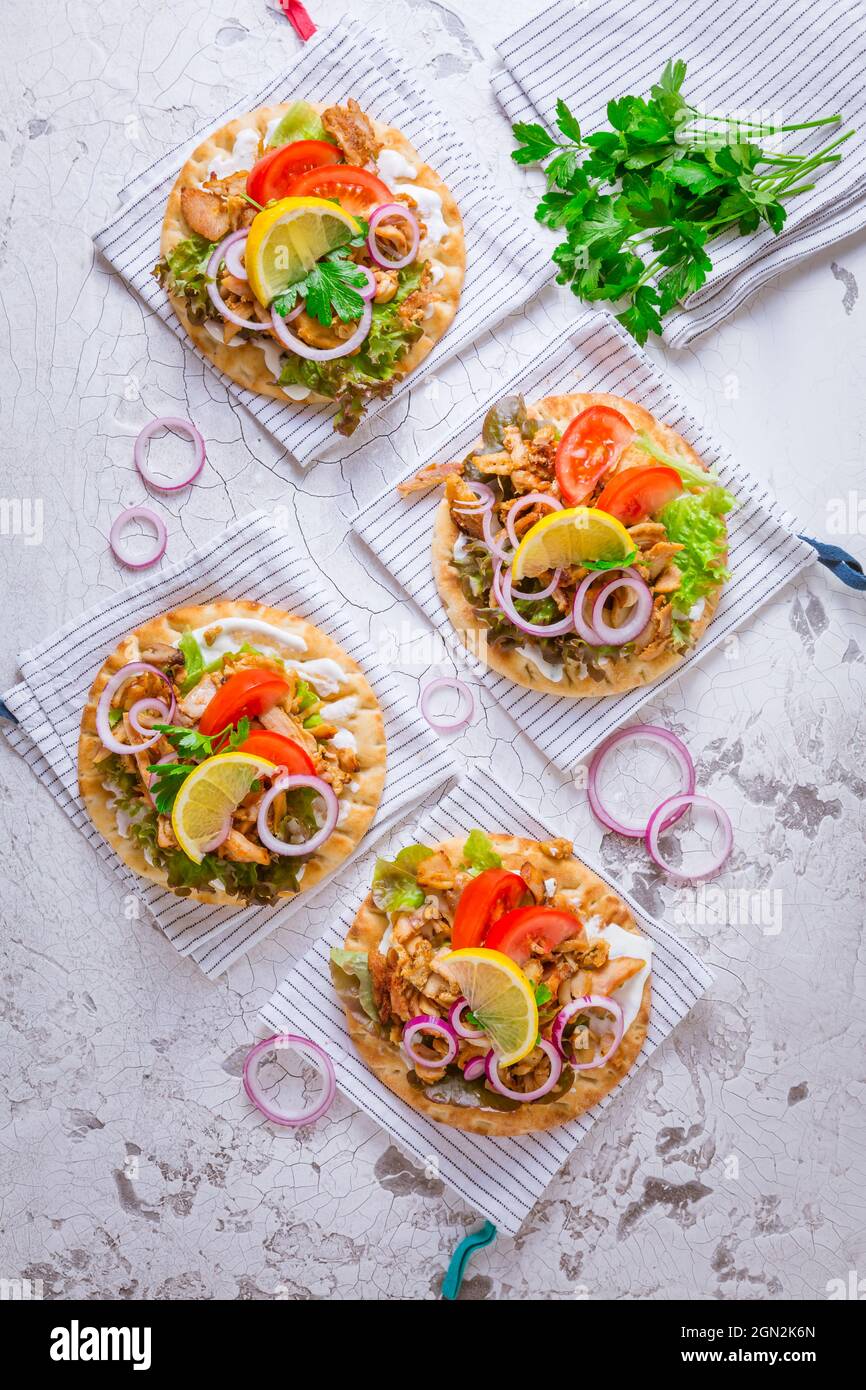 Greek gyros meat with pita flat bread, vegetables and onions and Tzatziki dip on white