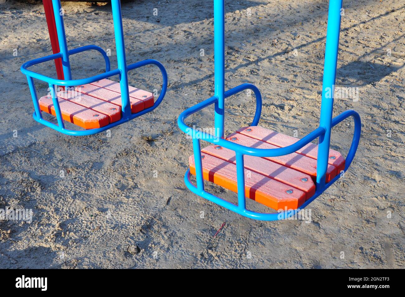 Metal colorful swings with wooden seat on children playground Stock Photo -  Alamy