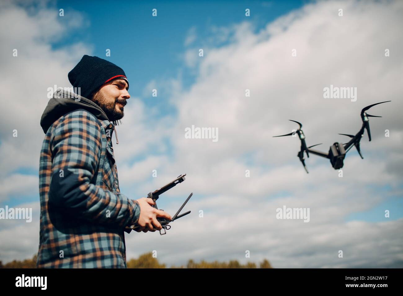 Man pilot controlling quadcopter drone with remote controller pad. Stock Photo