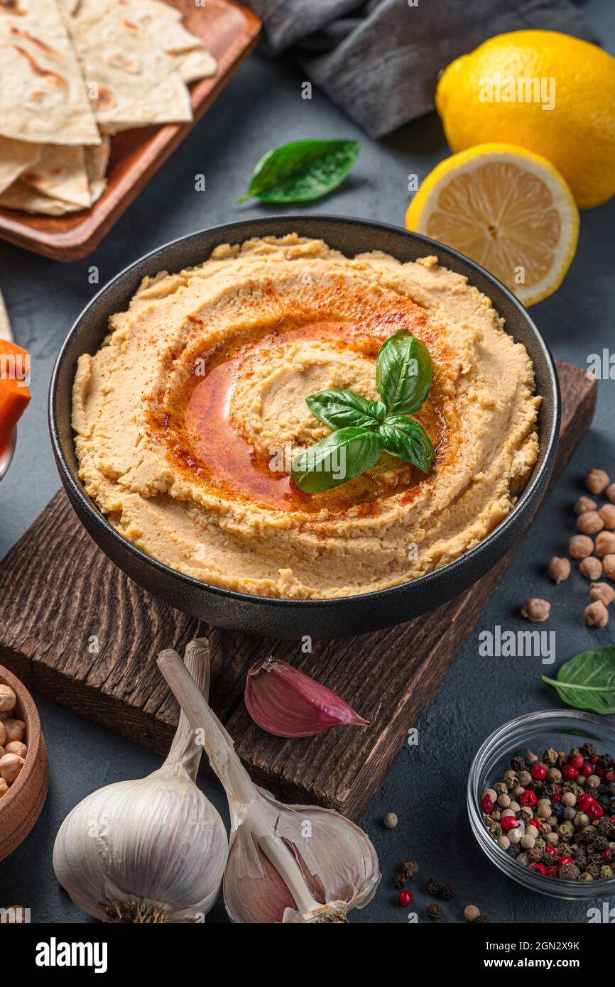 Hummus and ingredients on a dark background. A traditional oriental ...
