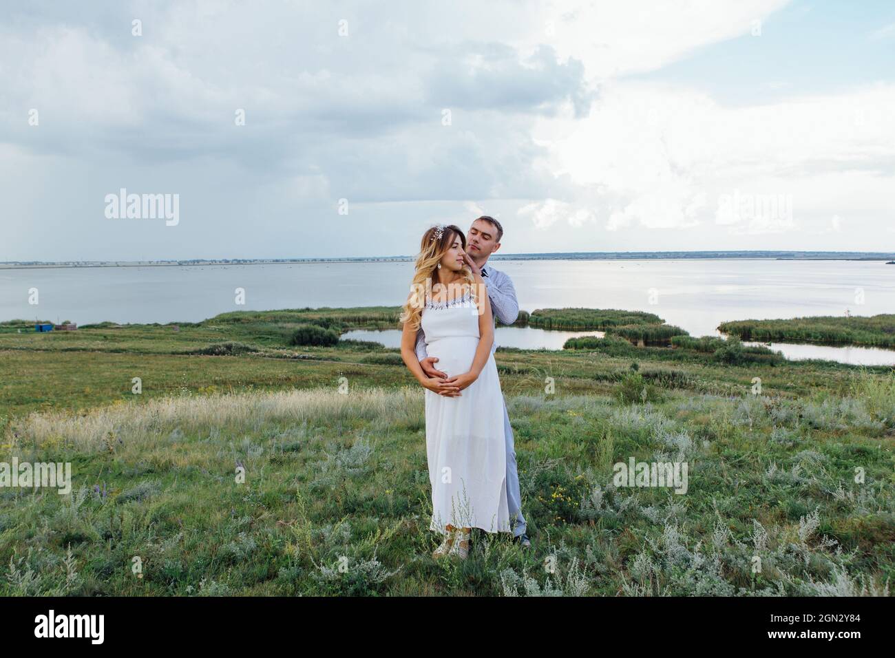 Happy young couple, expecting a baby. Man hugs his pretty pregnant ...