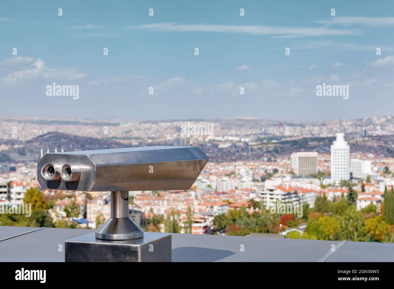 Coin operated binocular viewer at the terrace floor of Atakule in front of blurry Ankara view. Stock Photo