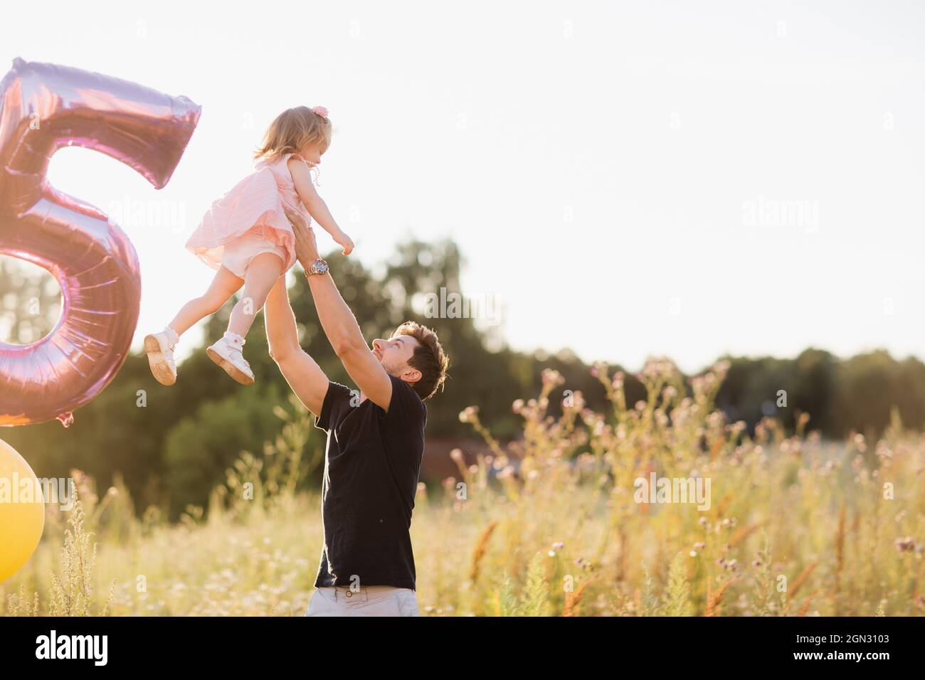 Dad and daughter are playing on the street, dad throws up the baby in