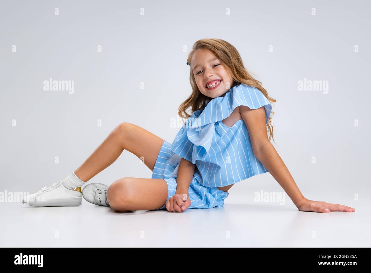 Beautiful little girl in blue holiday outfit sitting on floor ...