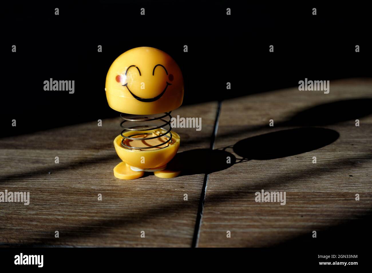yellow smiling emoji toy in the sun Stock Photo
