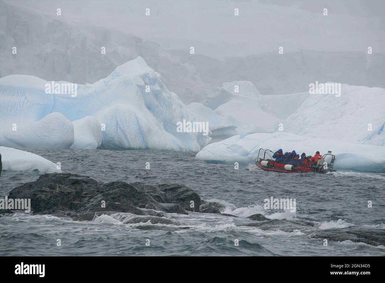 Group of people sailing on a small boat in the cold waters of ...