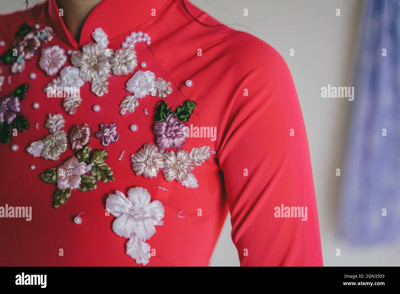 Closeup shot of a woman wearing a red sweatshirt with beautiful embroidered flowers on i Stock Photo