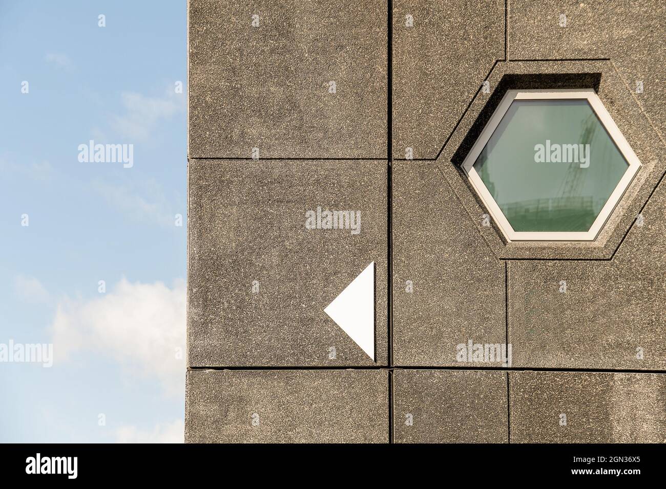 Concrete wall with hexagon window of modern building against blue sky ...
