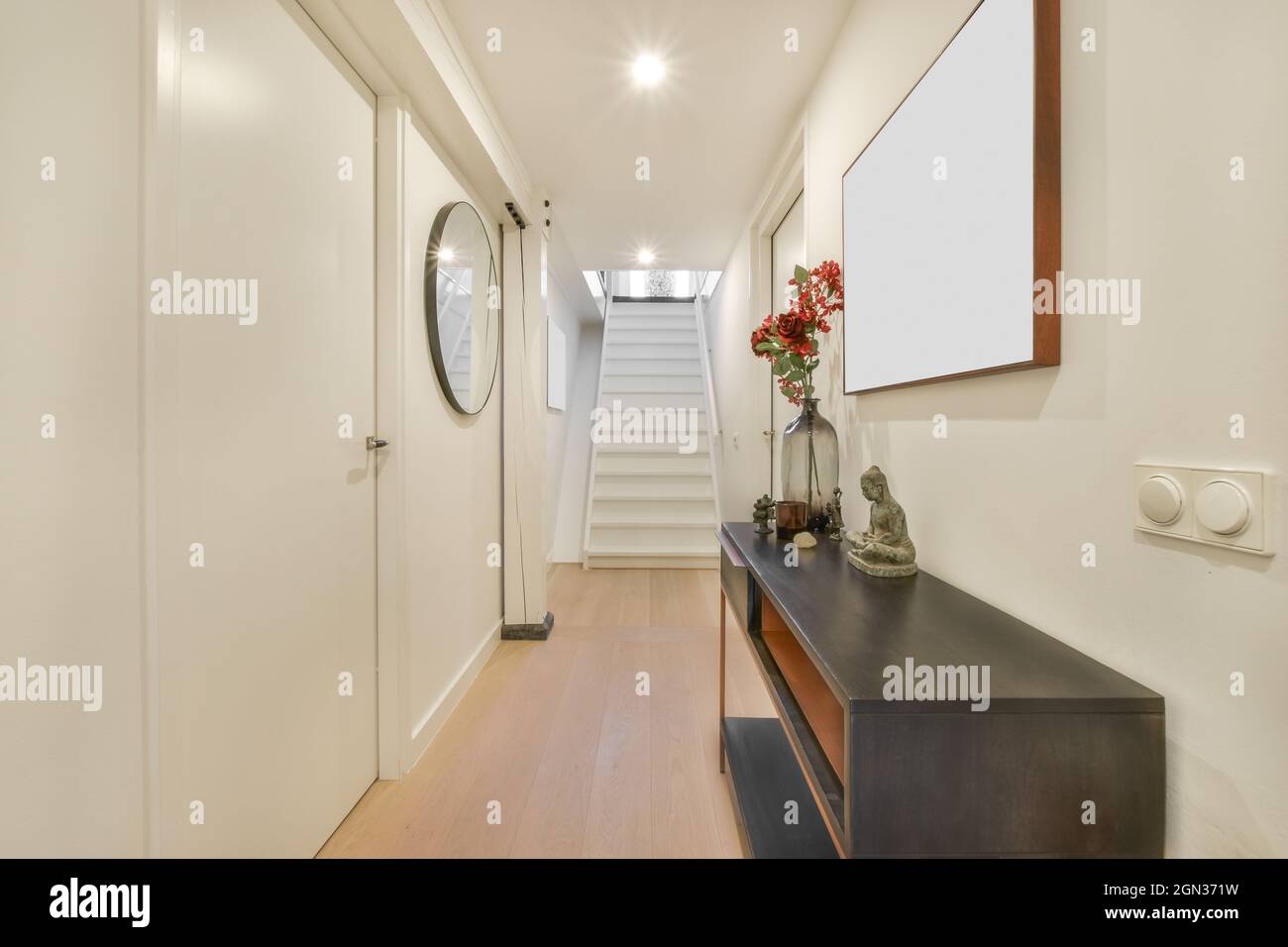 Modern hall interior with statuette and blossoming flowers in vase on