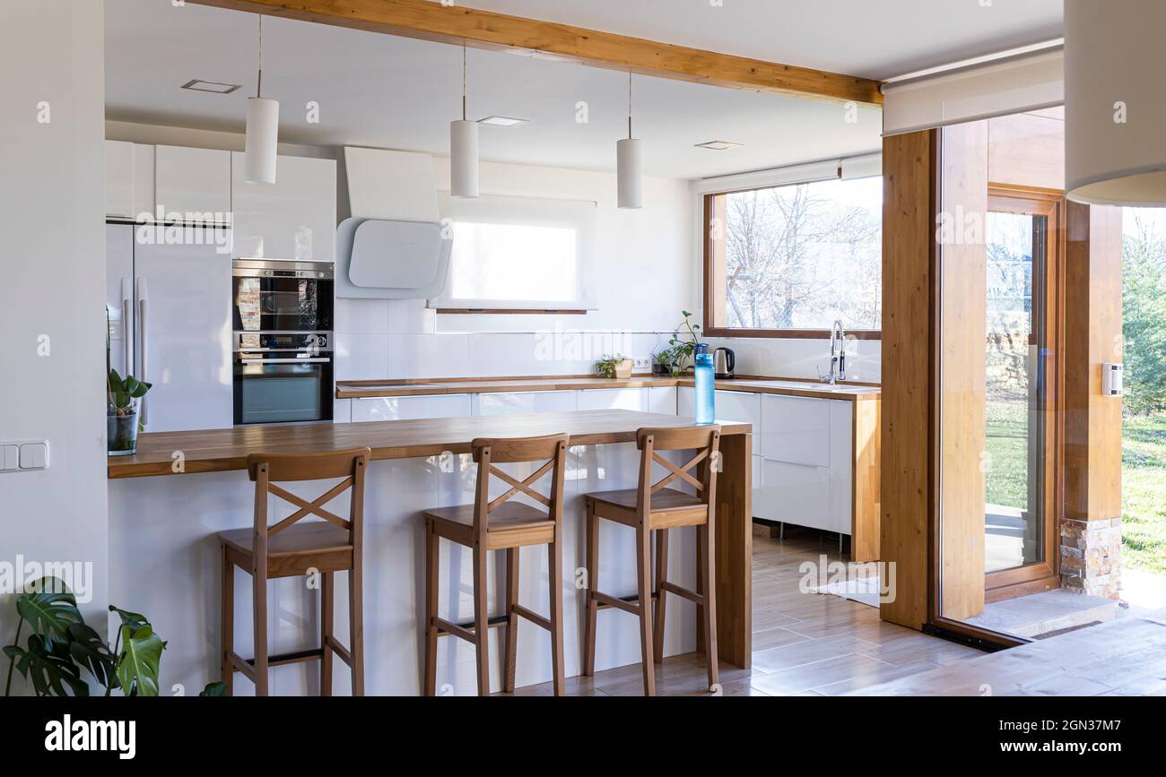 Corner of stylish kitchen with white and brick walls, wooden floor ...